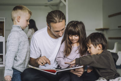 Teacher reading story book with students in child care center