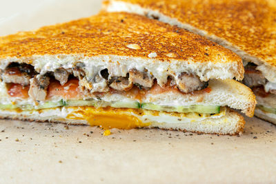 Close-up of two fresh crispy sandwich of toasted bread, fried eggs, cucumber, meat, cheese