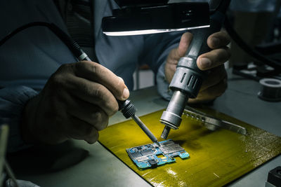 Midsection of person repairing computer chip in workshop