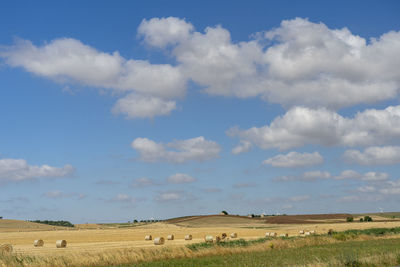 Hay bales on field against sky