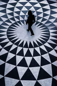 High angle view of boy shadow on tiled floor