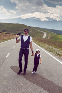 Father teaches son to ride a black skateboard on the road against  of mount everest in the summer