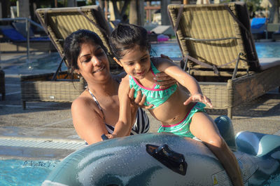 Mother assisting daughter in sitting on inflatable