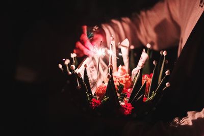 Low angle view of hand against illuminated fire in the dark