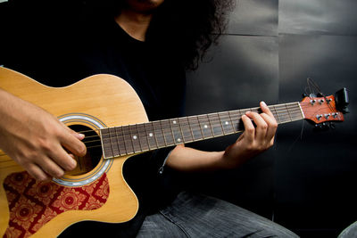 Midsection of man playing guitar