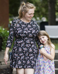 Happy mother and daughter standing at park