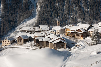 Snow covered houses on field by buildings