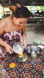 Woman pouring egg yolk in pumpkin on table