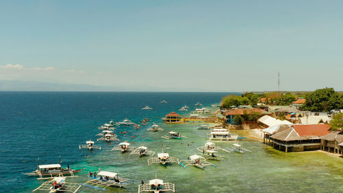 People snorkeling over coral reef with clear blue ocean water, top view. moalboal, philippines. 
