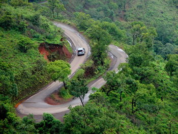 High angle view of winding road amidst trees in forest