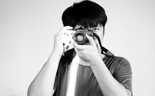 Portrait of man photographing against white background