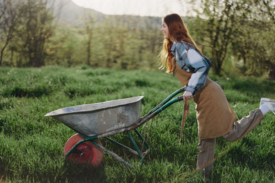 Playful woman with wheelbarrow in field