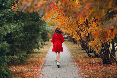 Rear view of woman walking on footpath during autumn