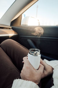 Midsection of woman drinking coffee in car