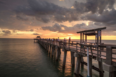 Pier on sea against sky during sunset