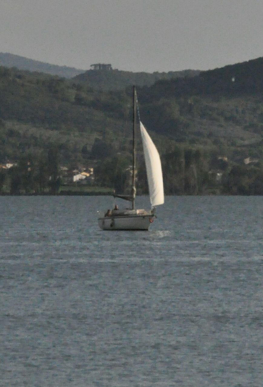 SAILBOAT SAILING ON SEA AGAINST MOUNTAIN