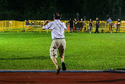 Rear view of man jumping on field in city during election at night
