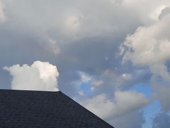 Low angle view of building roof against cloudy sky