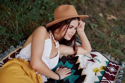 Side view of young woman sitting on field