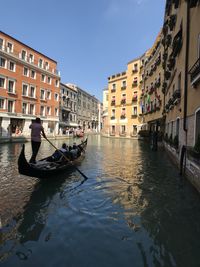 Canal amidst buildings in city against sky