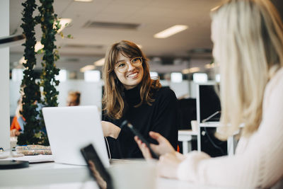 Portrait of a smiling young woman using phone