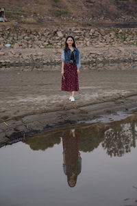 Full length of woman standing by lake