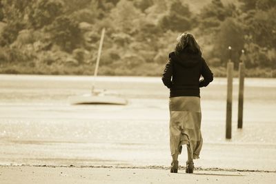 Rear view of woman with umbrella against trees