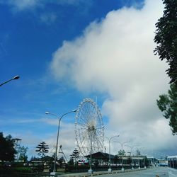 Ferris wheel in city against cloudy sky