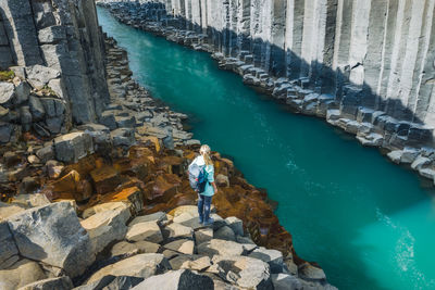 High angle view of man standing on rock by sea