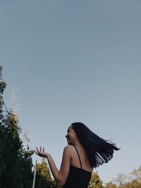 Woman standing by tree against clear sky