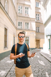 Full length of man holding mobile phone in building