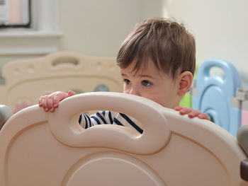 Pretty boy toddler in his playpen at home