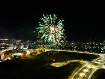 Firework display in city against sky at night