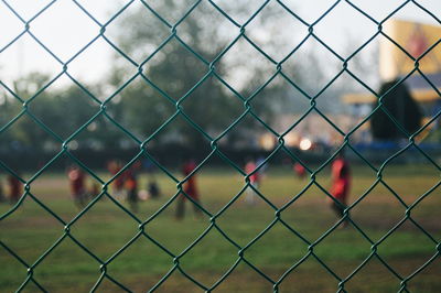 People on soccer field seen through chainlink fence