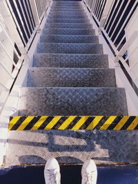 Low section of man standing on steps at subway station