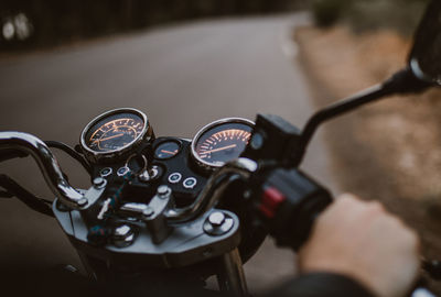 Person crop driving on motorcycle on asphalt route between forest