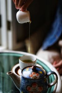 Cropped image of person pouring coffee in cup