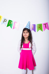 Portrait of smiling young woman standing against wall