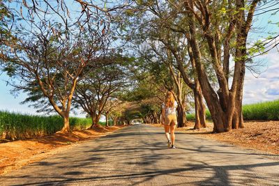 Rear view of woman walking on road amidst trees