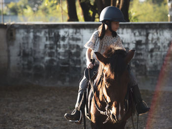 Asian school kid girl with horse ,riding or practicing horse ridding at horse ranch.