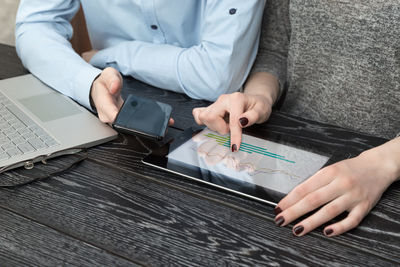 Midsection of man using mobile phone on table
