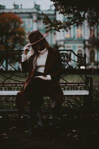 Full length of woman sitting on bench at park