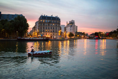 People in river against sky during sunset