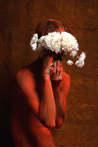 Man with flowers standing against wall