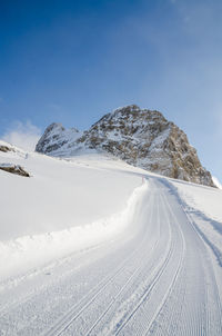 Ski track on snow covered mountain against sky, grindelwald, switzerland