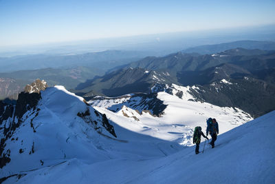 Two athletes hike up a glacier on mt. baker in the shadow of the summit.