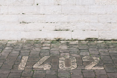 High angle view of numbers on footpath against wall