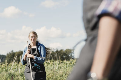 Female farmer with coworker on farm against sky