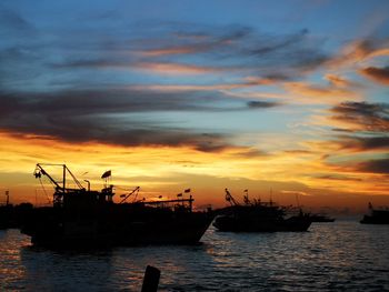 Silhouette boats in sea against sky during sunset