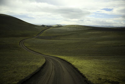 Empty road leading towards mountains against sky